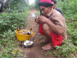 This man is calling back the spirit for someone who is sick. They believe that if someones spirit leaves they die. Therefore they have a long solemn procedure to try to get the spirit back. He has cooked rice and uncooked rice, beer, and some green leaves. He has to tap the stick on the ground 100 times while he chants, then he blows on a small cup of rice and places it under a string. This is repeated over and over again.